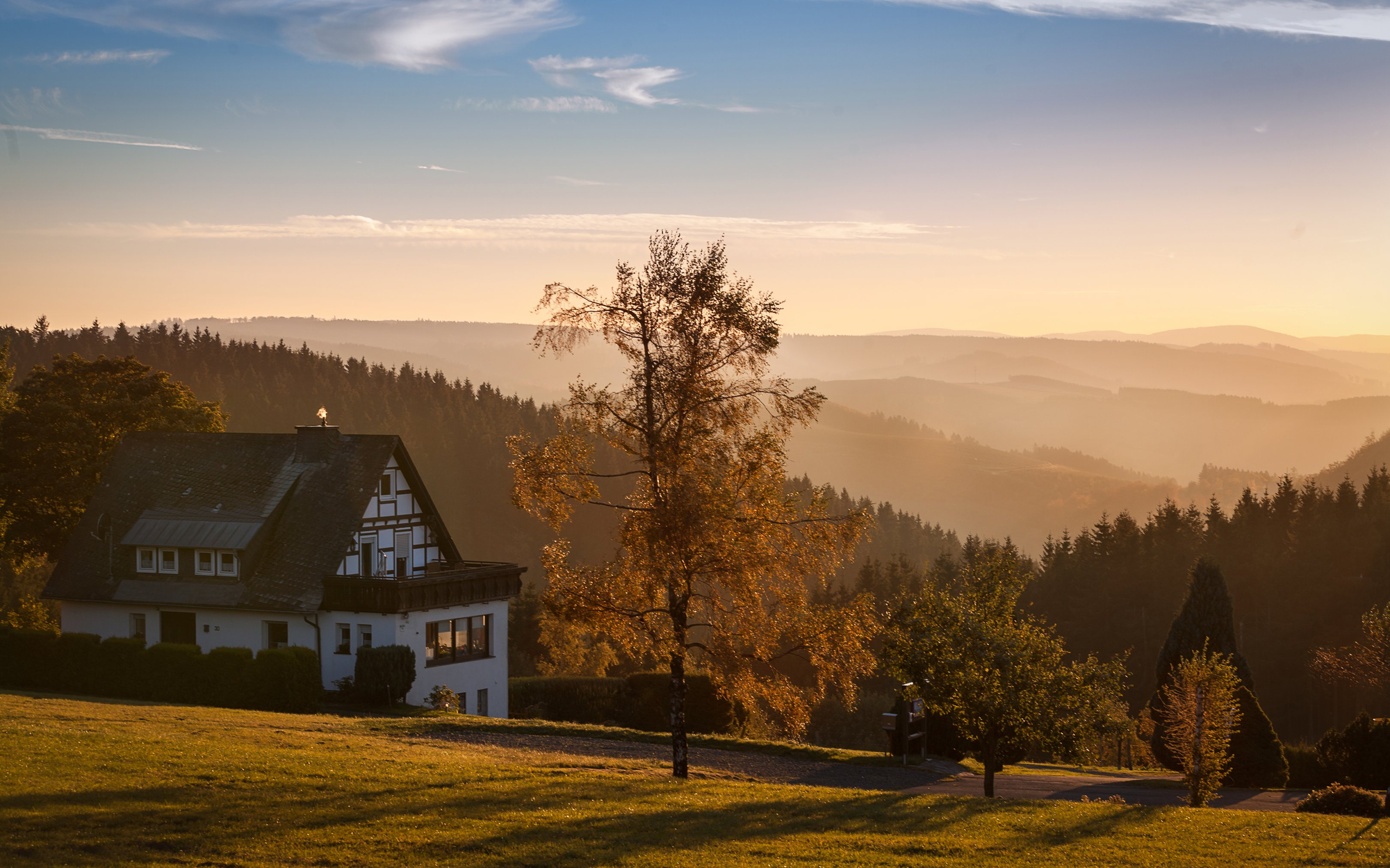 Die Landschaft rund um die Ortschaft Lenneplätze mit Wäldern und Bergen in der Abendsonne.