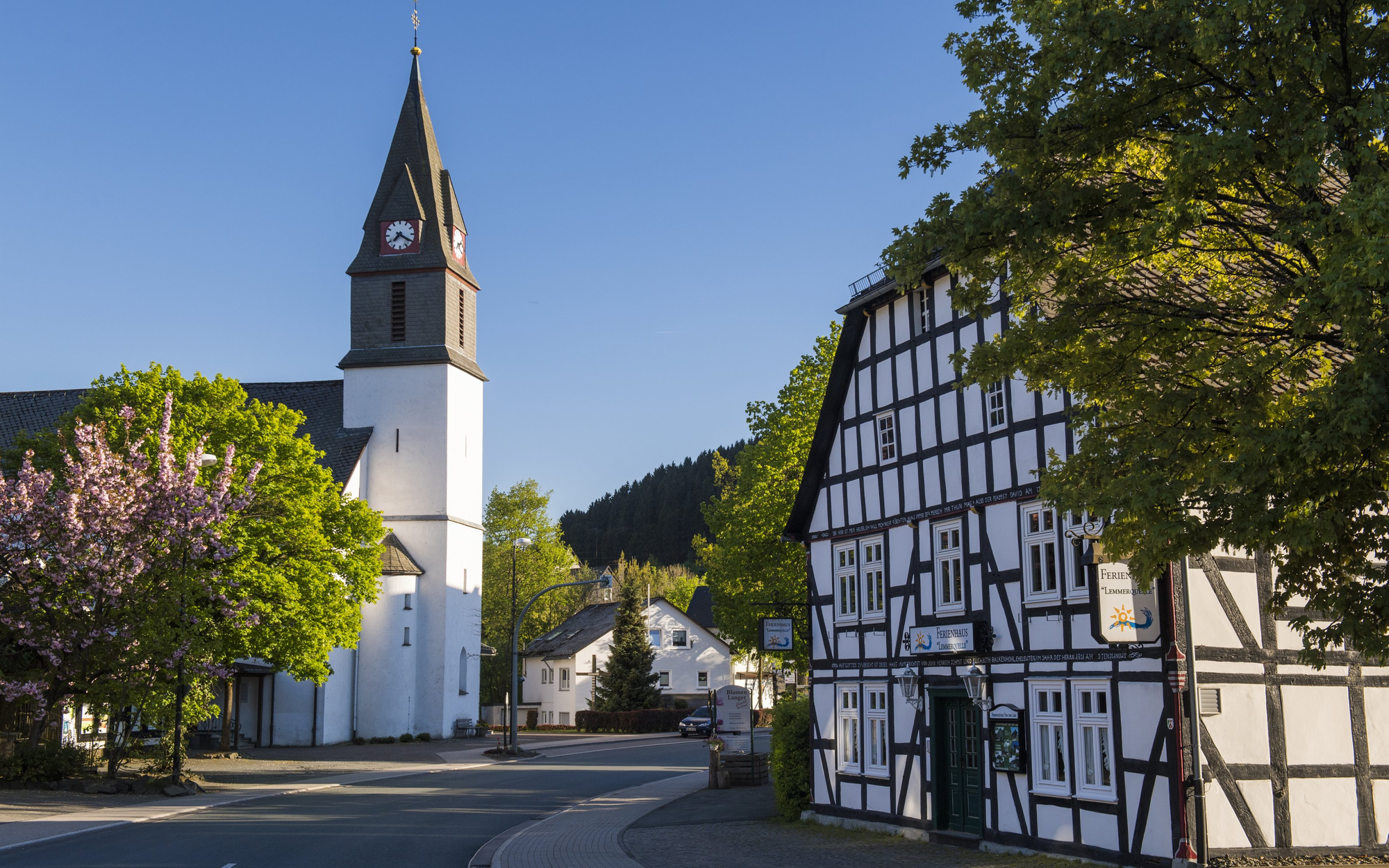 FerienweltWinterberg_2018_Niedersfeld_Ortsansicht_Fachwerk_St_Agatha_Kirche_Sommer Die Ortsdruchfahrt der Ortschaft Niedersfeld mit Kirche und Fachwerkhaus.