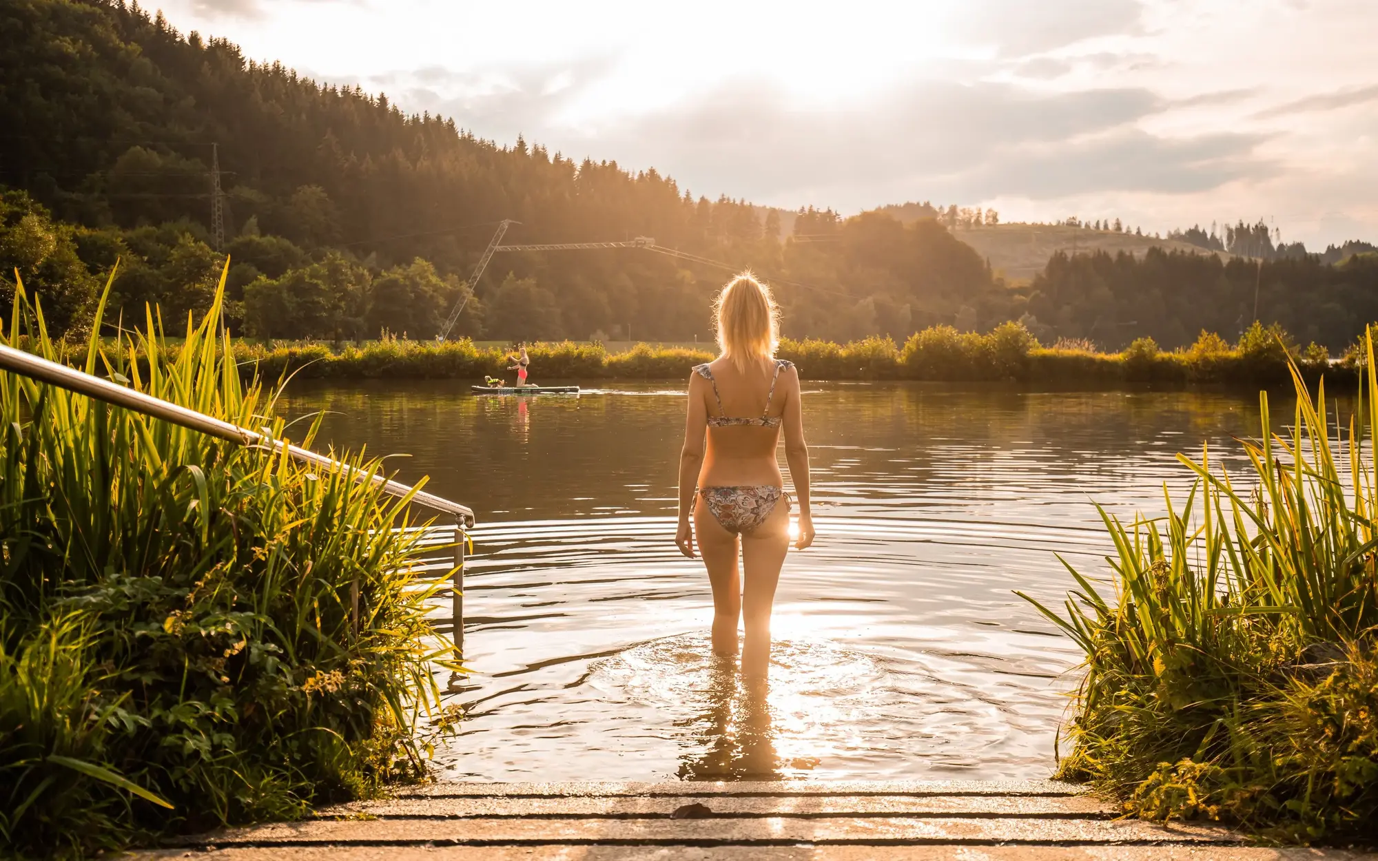 Eine Frau geht zum schwimmen in den See.