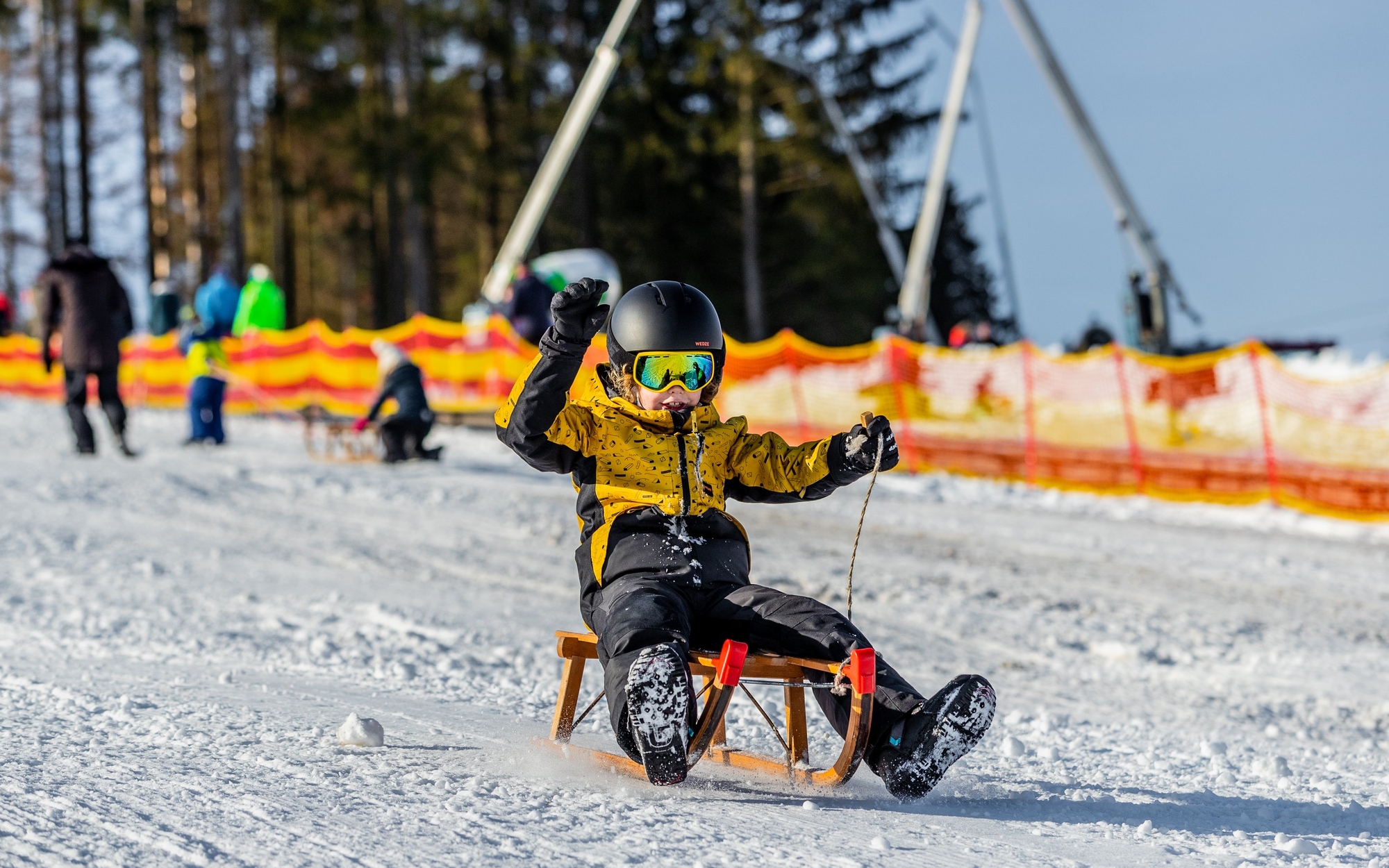 Ruhrquelle_Schlitten_rodeln_Schnee Ein KInd fährt auf seinem Schlitten ein Rodelhang hinunter.