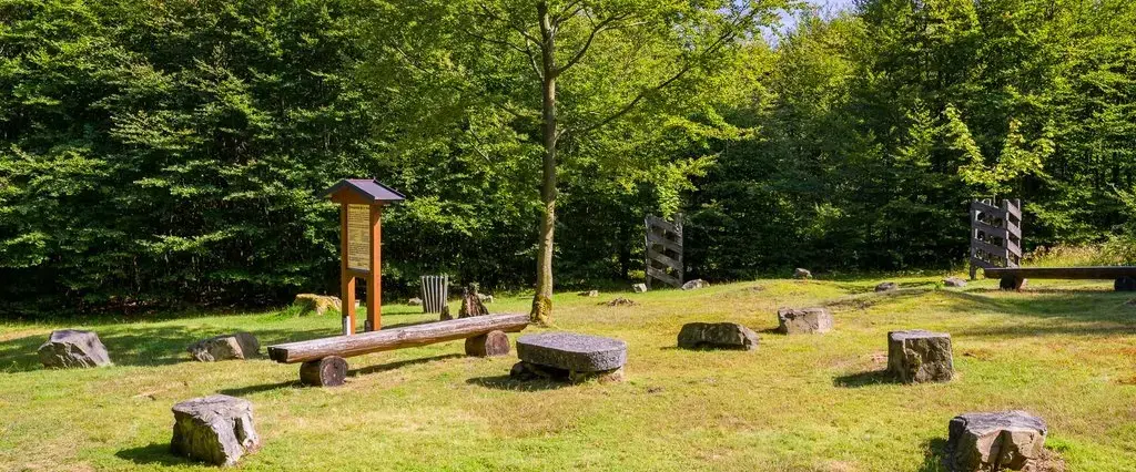 Ein Platz mit Bänken und großen Steinen auf einer Wiese.