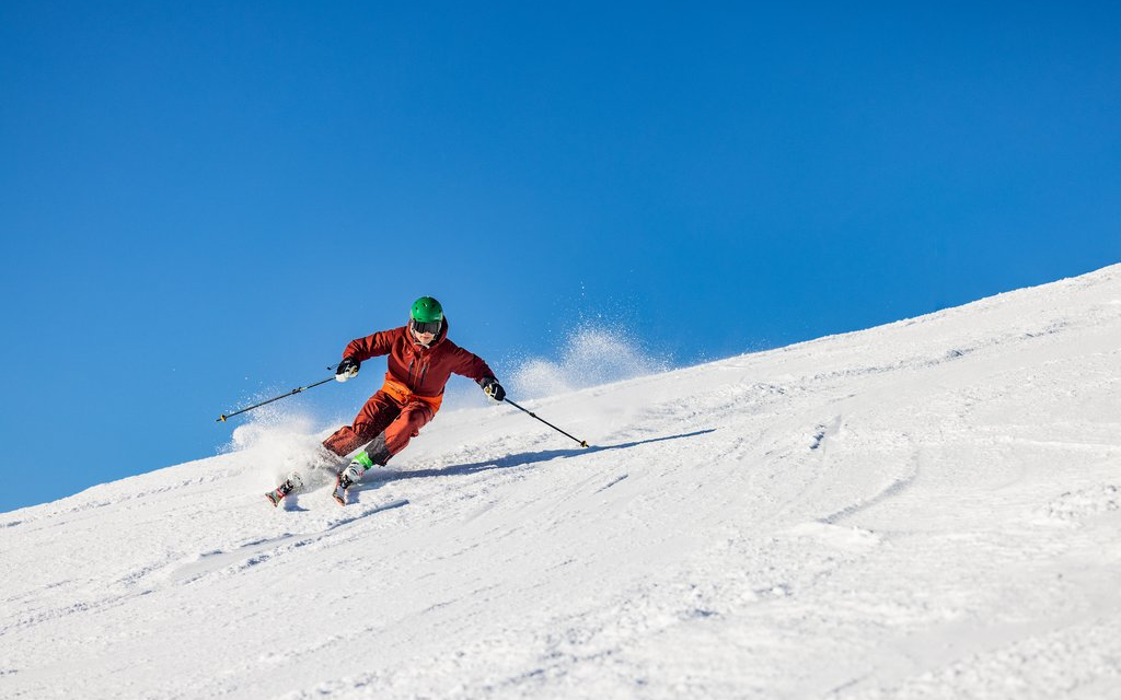 Skifahrer fährt bei Sonnenschein eine Piste im Skiliftkarussell Winterberg hinunter.