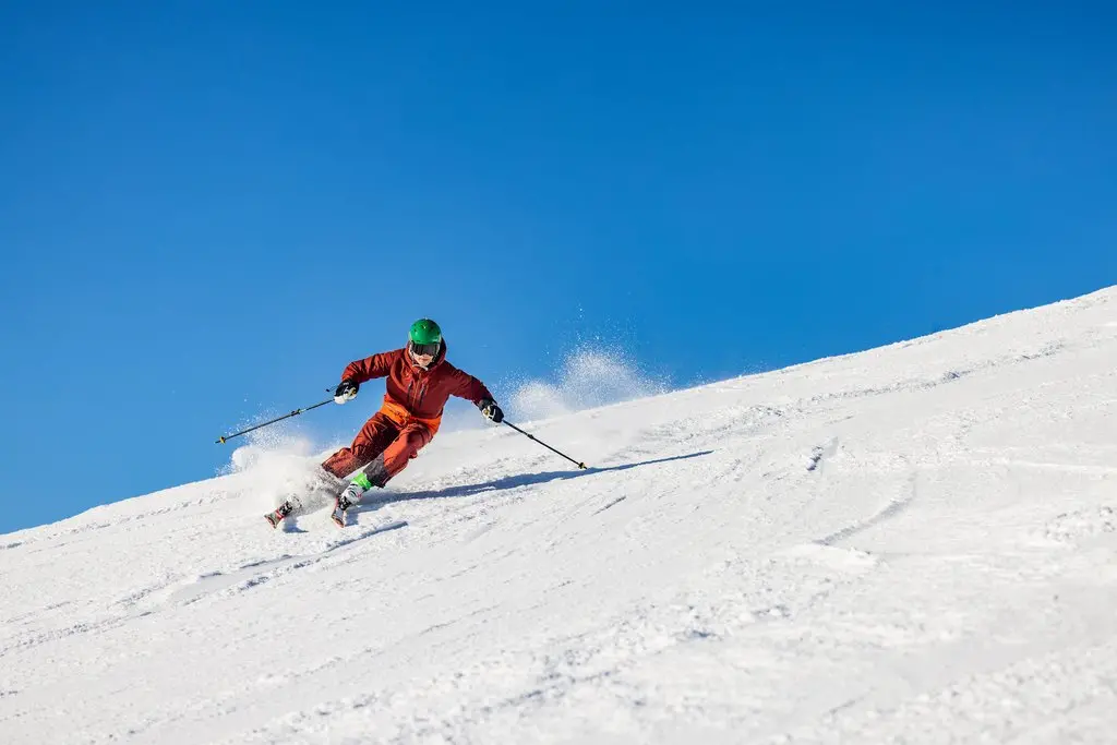 Skifahrer fährt bei Sonnenschein eine Piste im Skiliftkarussell Winterberg hinunter.