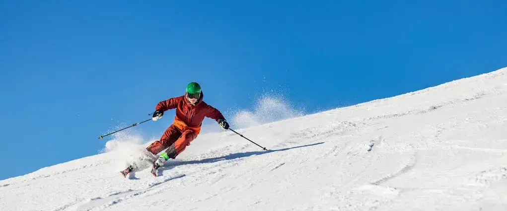 Skifahrer fährt bei Sonnenschein eine Piste im Skiliftkarussell Winterberg hinunter.