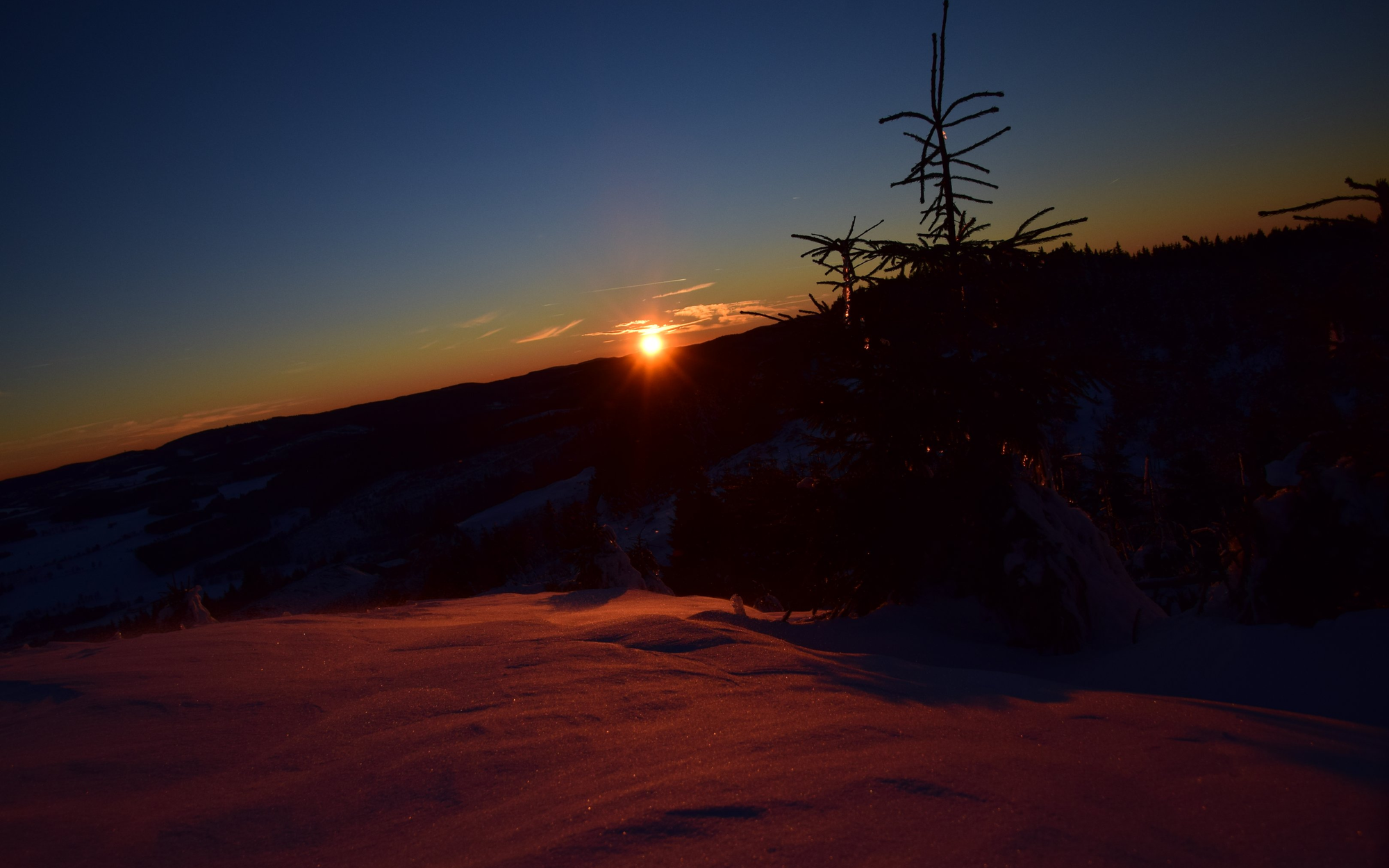 Eine schneebedeckte Landschaft bei Sonnenuntergang.