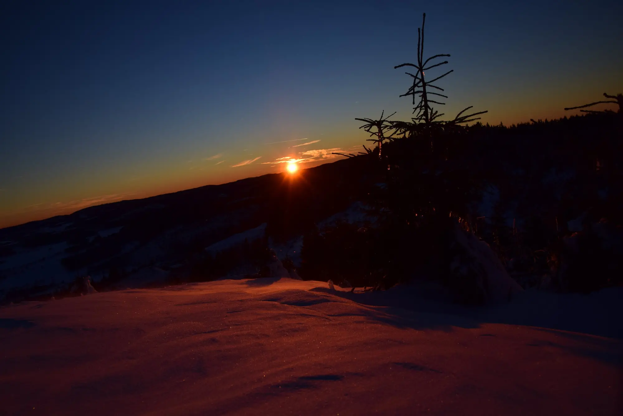 Eine schneebedeckte Landschaft bei Sonnenuntergang.