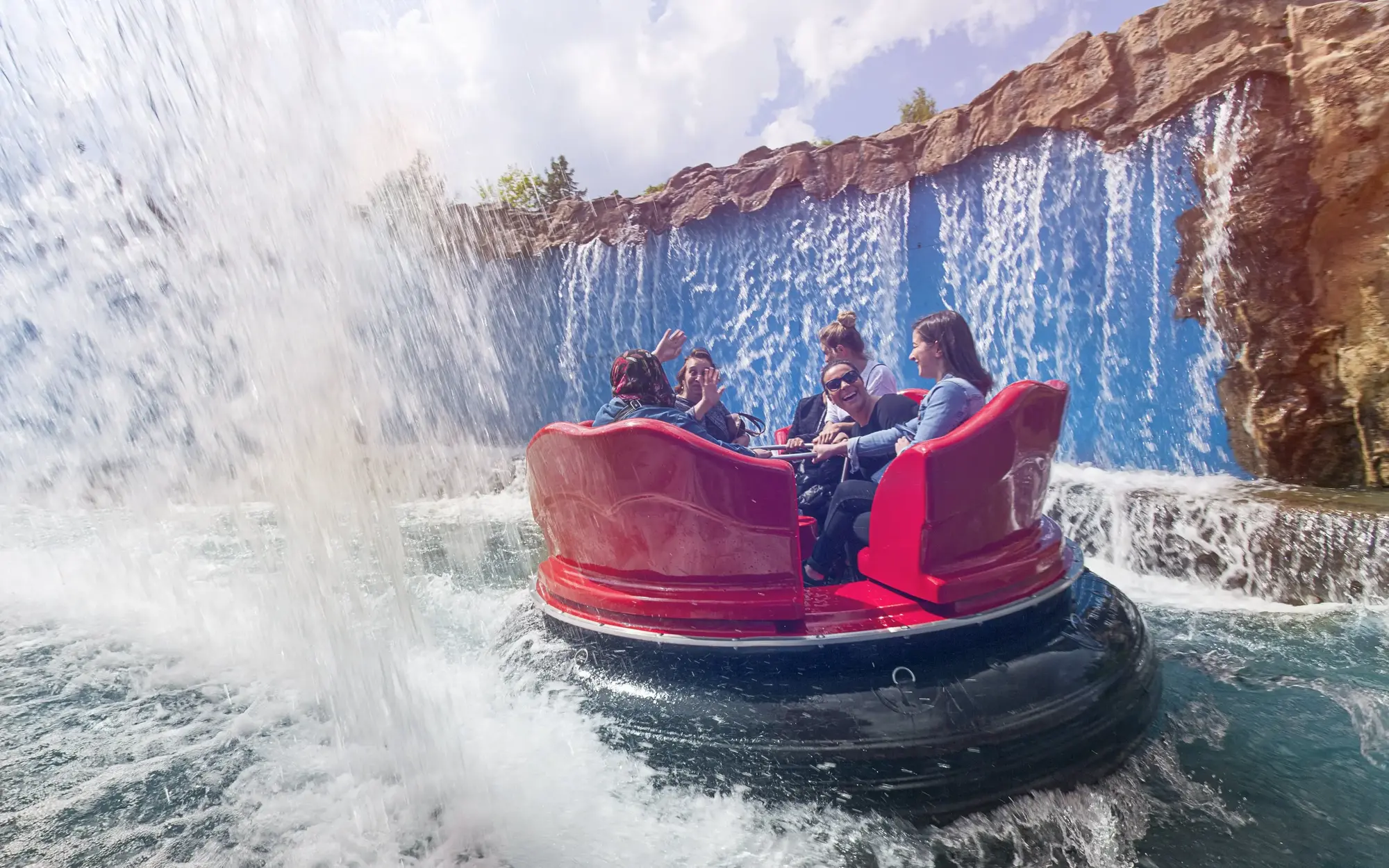 Ein rundes Boot mit 5 Personen, die im RioGrande im Fort Fun Abenteuerland zwischen zwei Wasserfällen hindurchfahren.