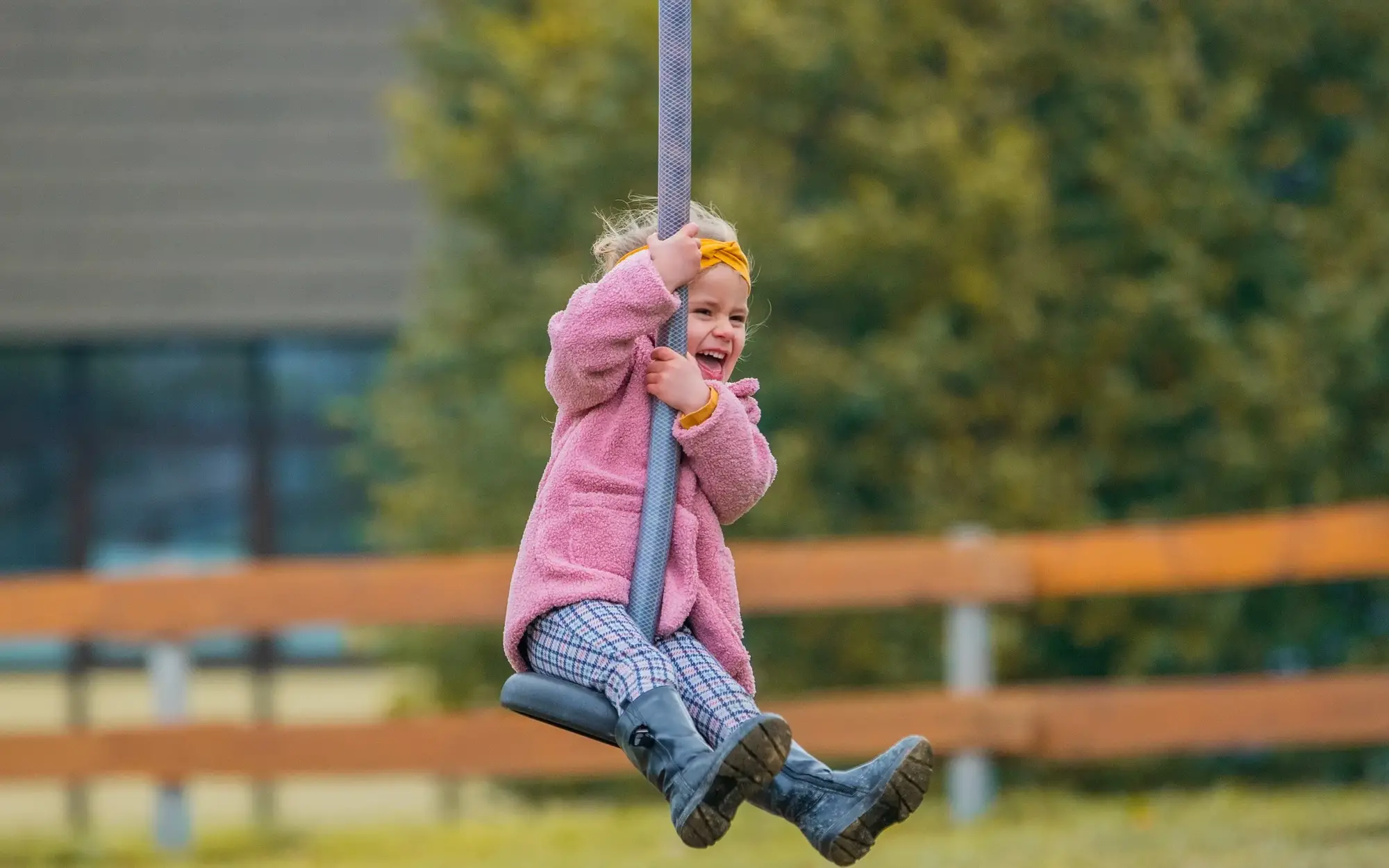 Kleines Mädchen lachend auf einer Seilrutsche auf dem Spielplatz