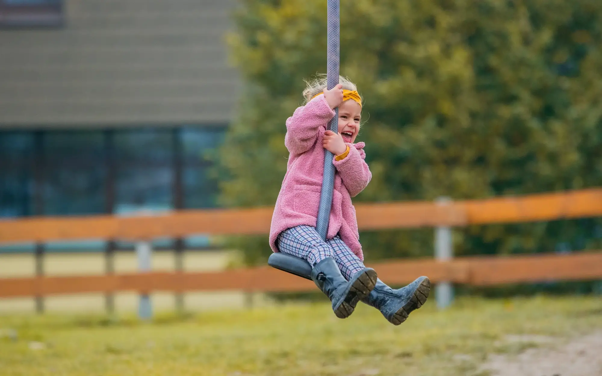Kleines Mädchen lachend auf einer Seilrutsche auf dem Spielplatz