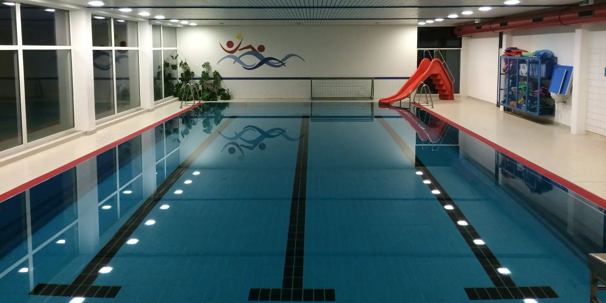 Das Sportbecken im Hallenbad von Siedlinghausen mit einer roten Wasserrutsche.