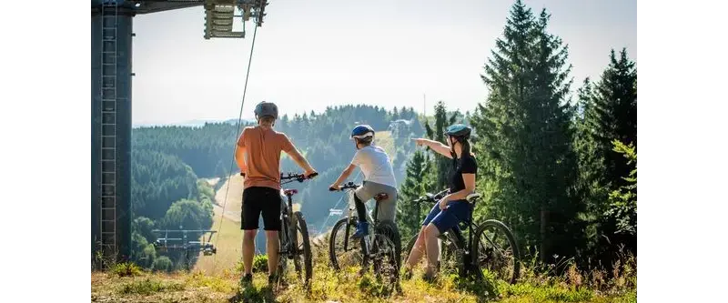 Drei Personen bei einer Mountainbiketour durch das Skiliftkarussell genießen die tolle Aussicht.