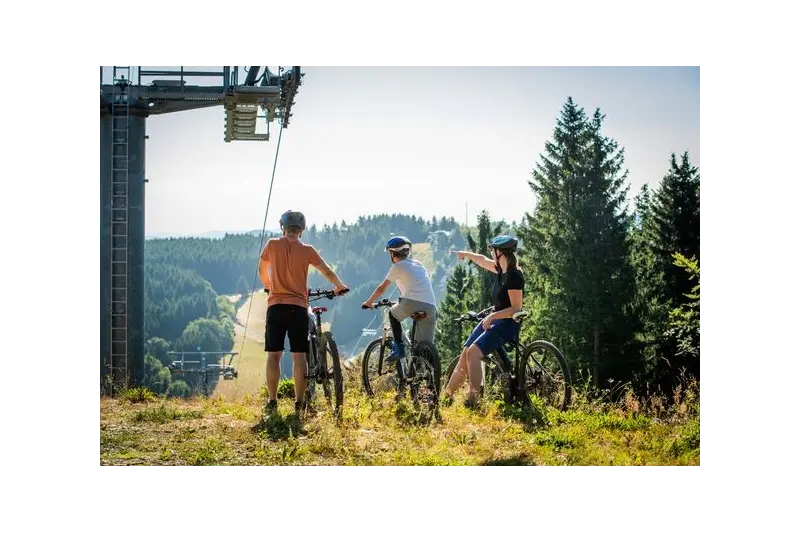 Drei Personen bei einer Mountainbiketour durch das Skiliftkarussell genießen die tolle Aussicht.