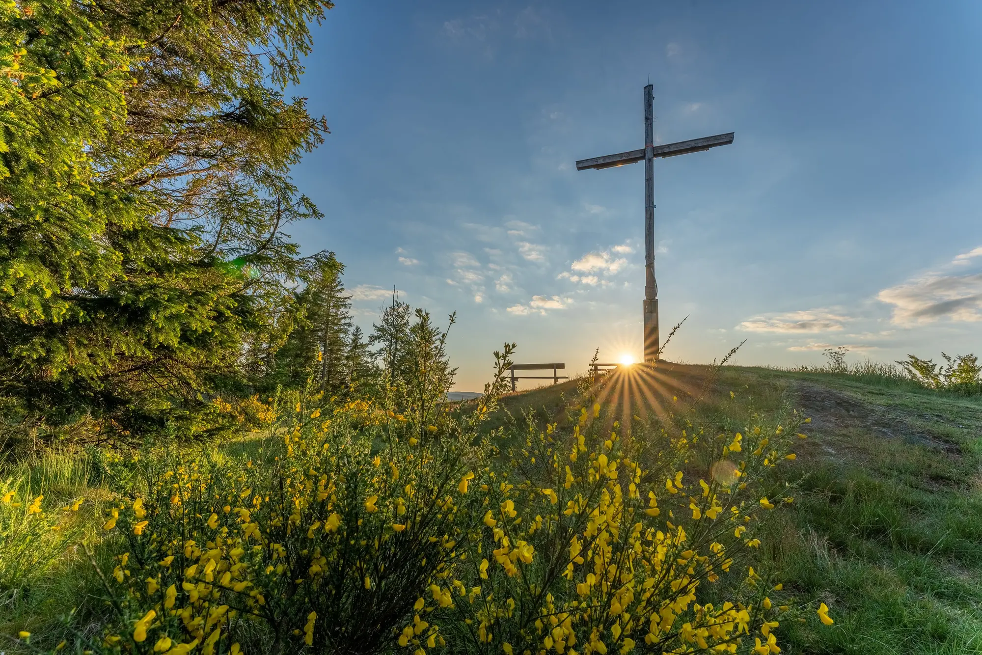 Das Kreuz auf dem Alten Grimmen mit aufgehender Sonne im Hintergrund.