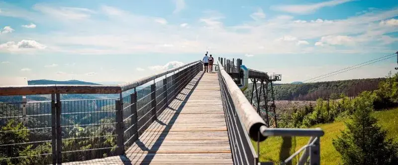 Zwei Personen gehen über die Panorama Erlebnisbrücke und genießen die Aussicht.