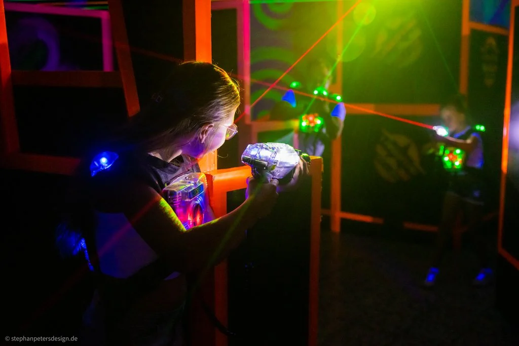 Winterberg_Freizeit_Lasertag_Laser_Frauen_schießen Zwei Frauen halten Laserpistolen in der Hand und versuchen sich gegenseitig im dunklen Raum mit den Lasern zu treffen.